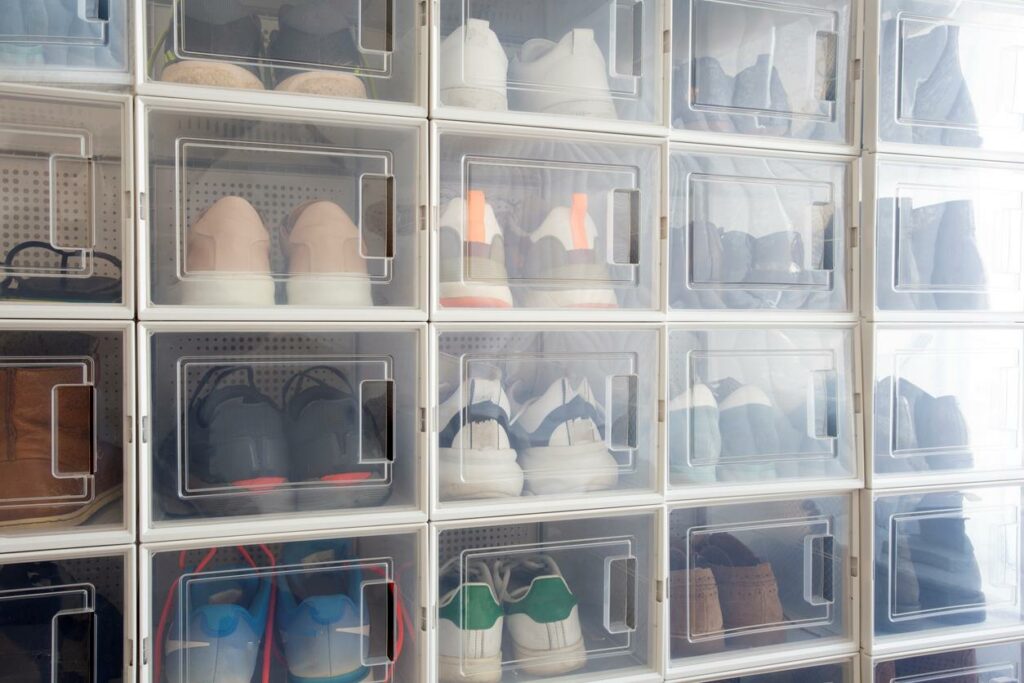 Several pairs of shoes are inside plastic clothing storage bins.