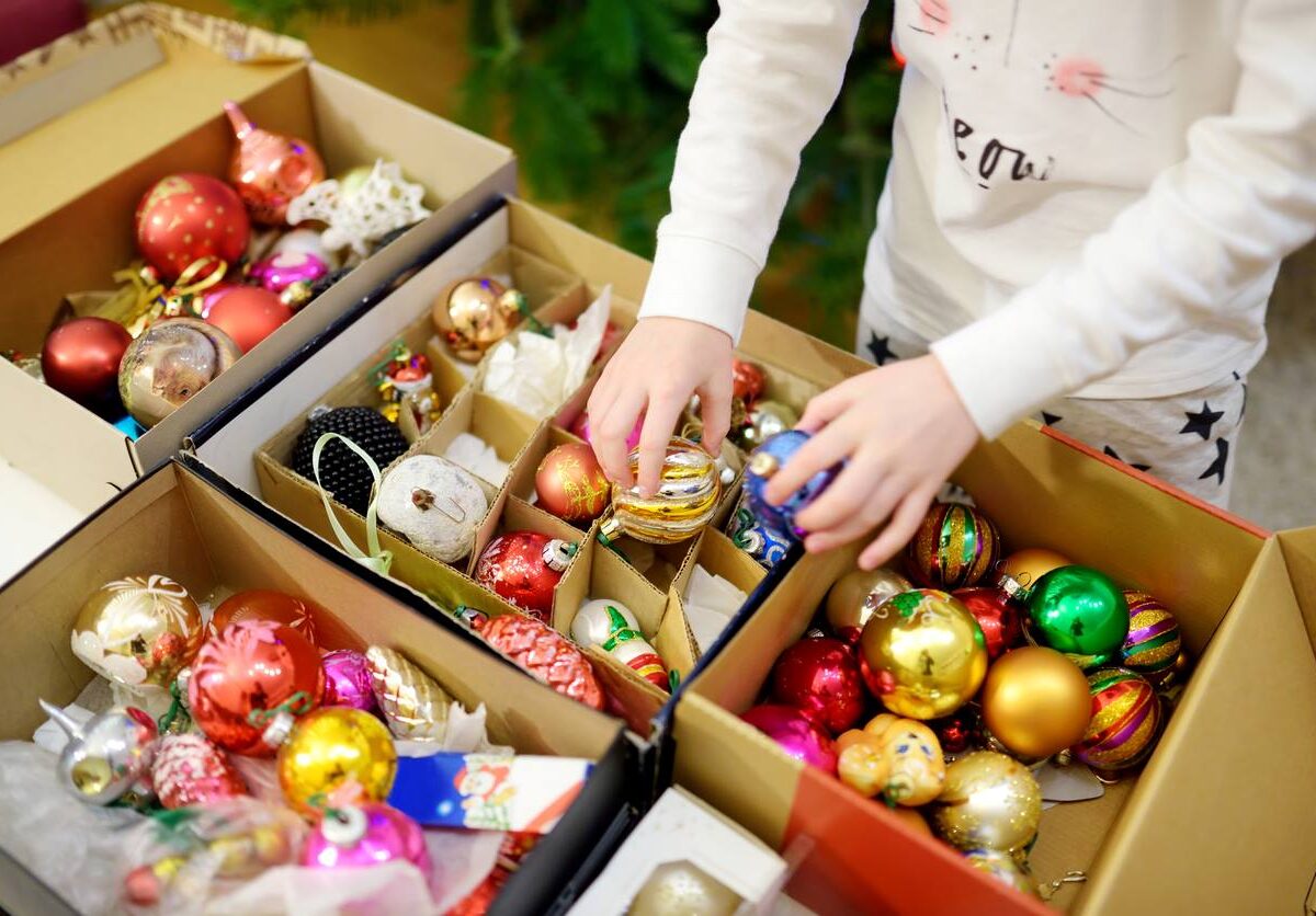 A boy unpacks Christmas ornaments from a holiday storage box.