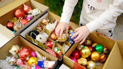 A boy unpacks Christmas ornaments from a holiday storage box.