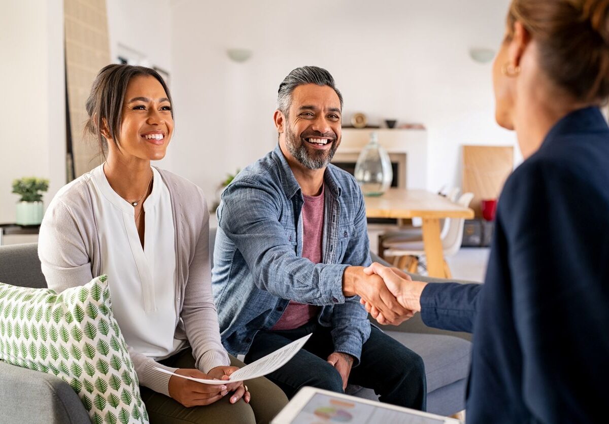 A happy couple smiles as they meet with a potential realtor.